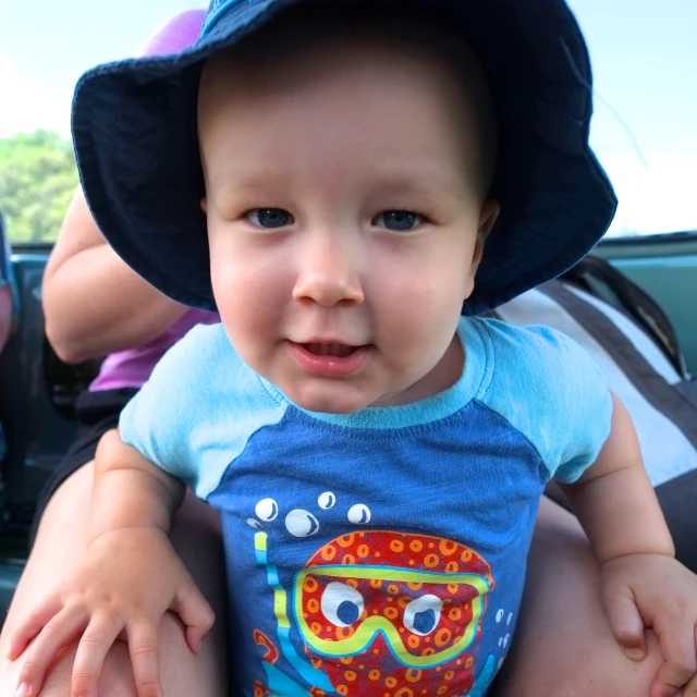 a small child is wearing a hat and sitting in the back seat of a car