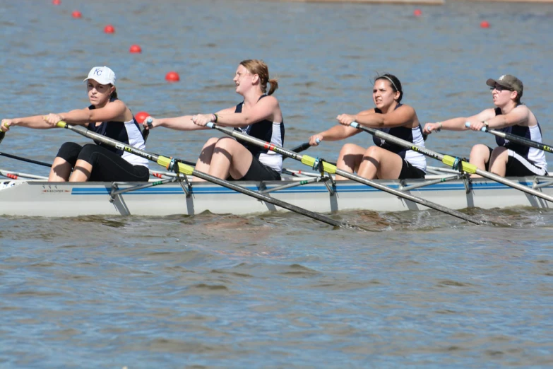 five women rowing in the water with sticks