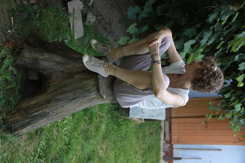 the young man is sitting on top of the log