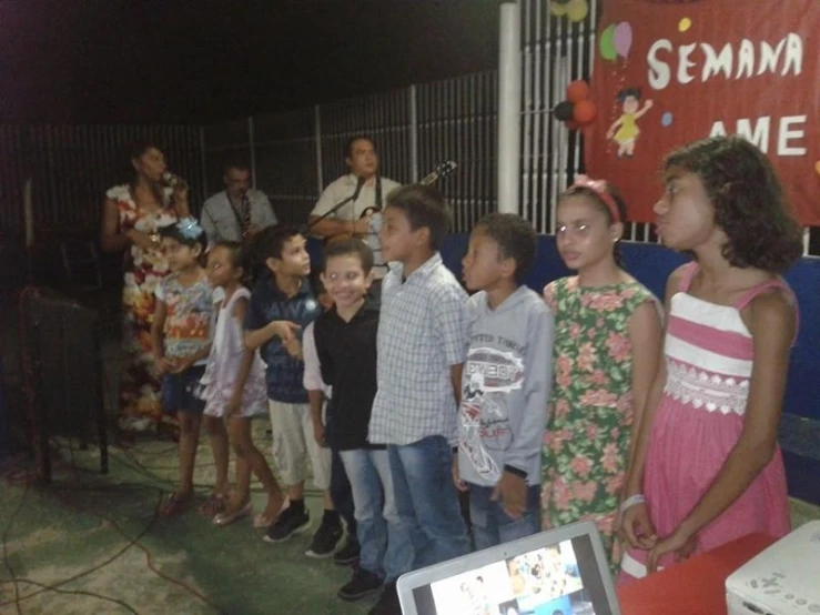 a group of children are standing by a wall with a laptop