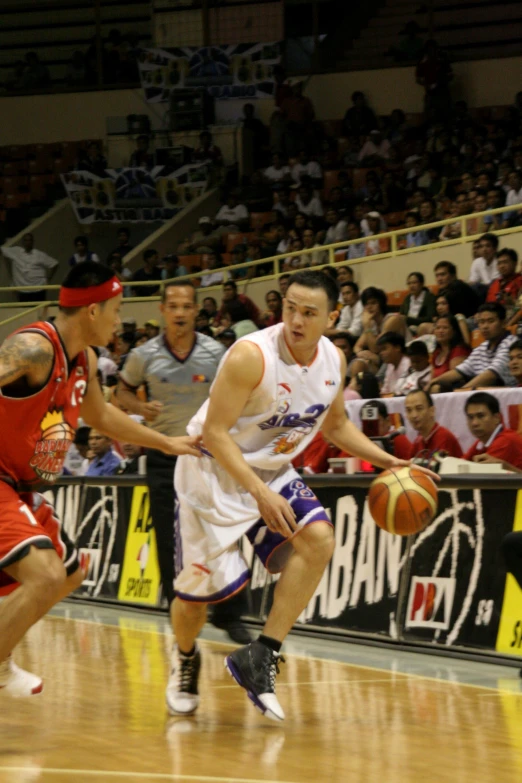 basketball players playing a game of basketball as a crowd watches