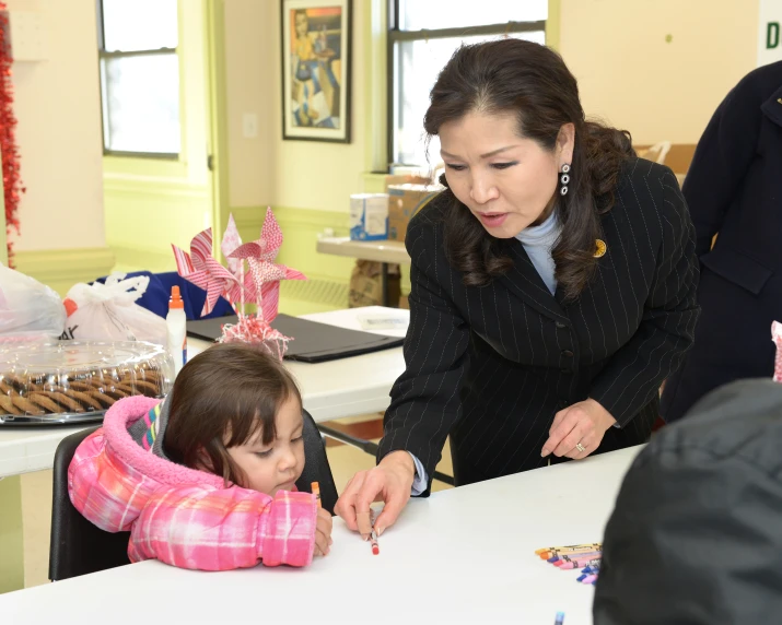 a woman standing next to a child while writing