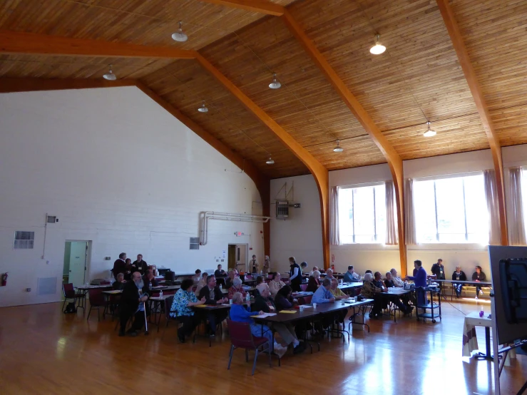 a group of people sitting around a wooden table in a gym