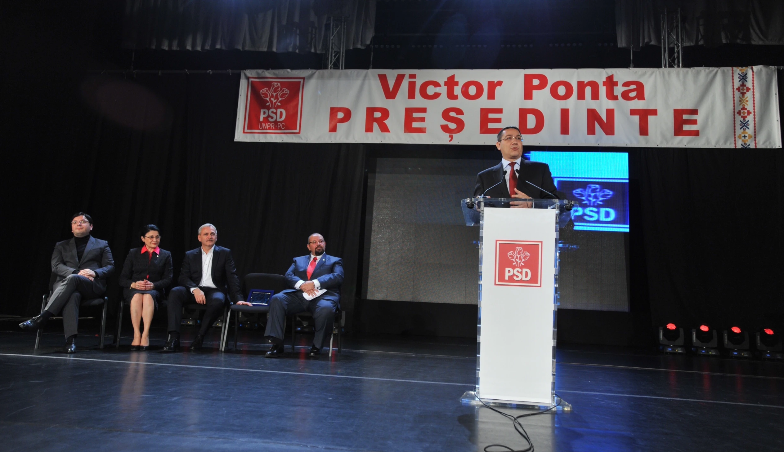 a man standing at a podium in front of others on stage