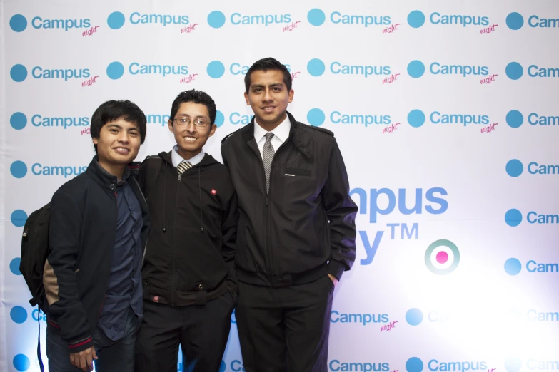 three men standing next to each other in front of a wall