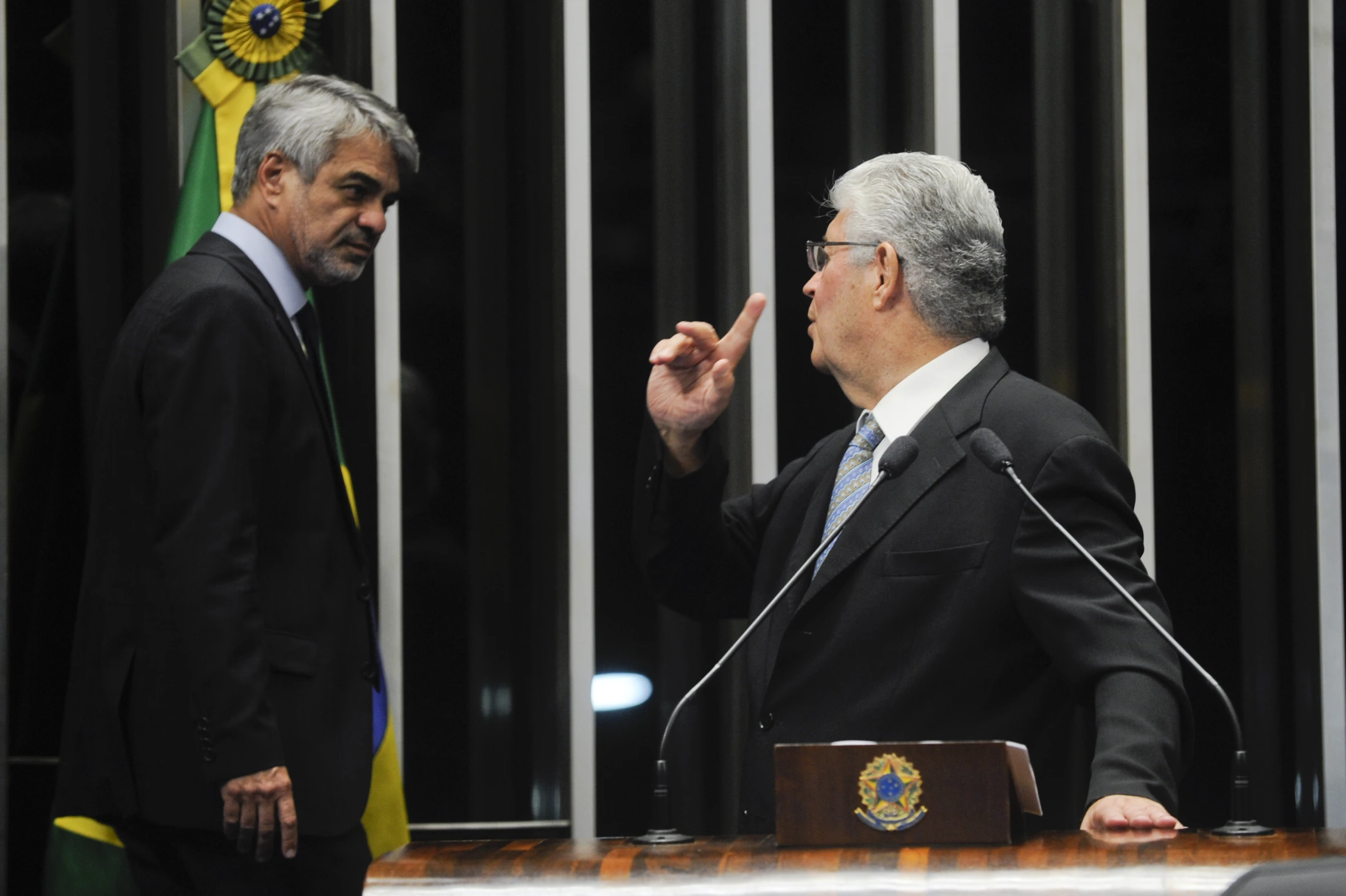 two men speaking to each other with flags behind them