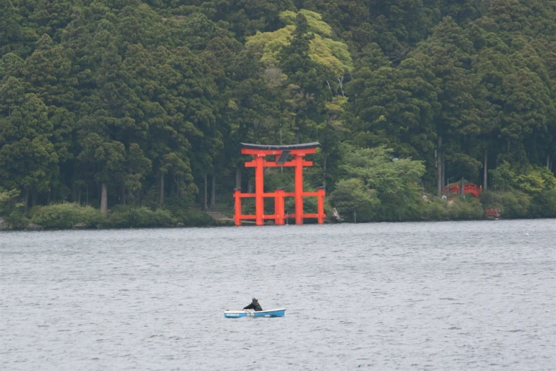 a man in a small boat with a red tori - te in the background