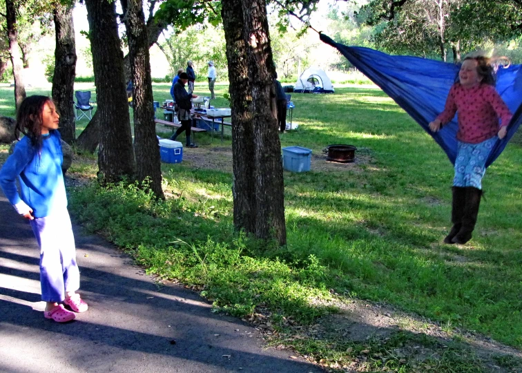 two girls are playing with a blue parachute