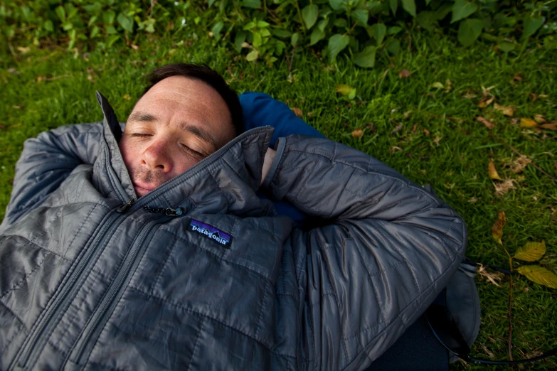 man laying on the ground while he covers his eyes with his jacket