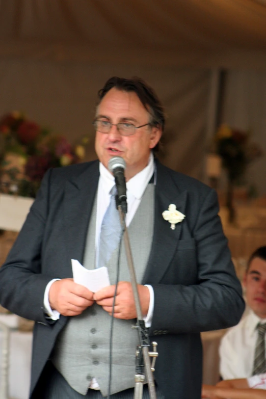 a man standing in front of a microphone while wearing glasses