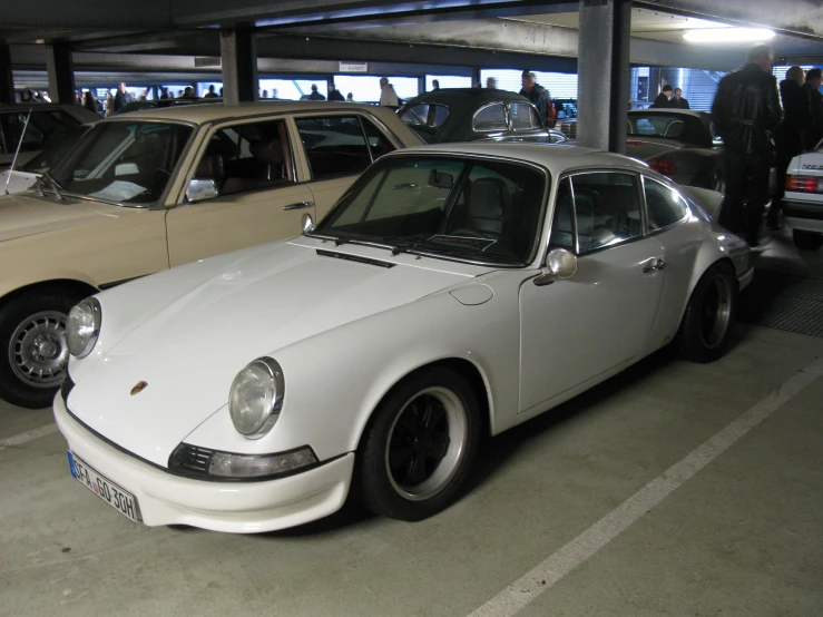 a white and tan porsche car sitting in a garage