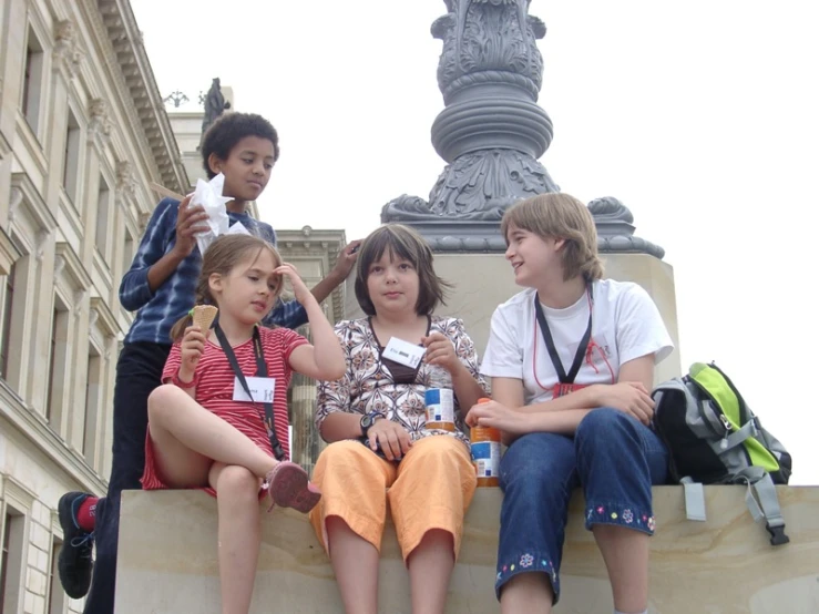 four children sitting on the steps near a statue