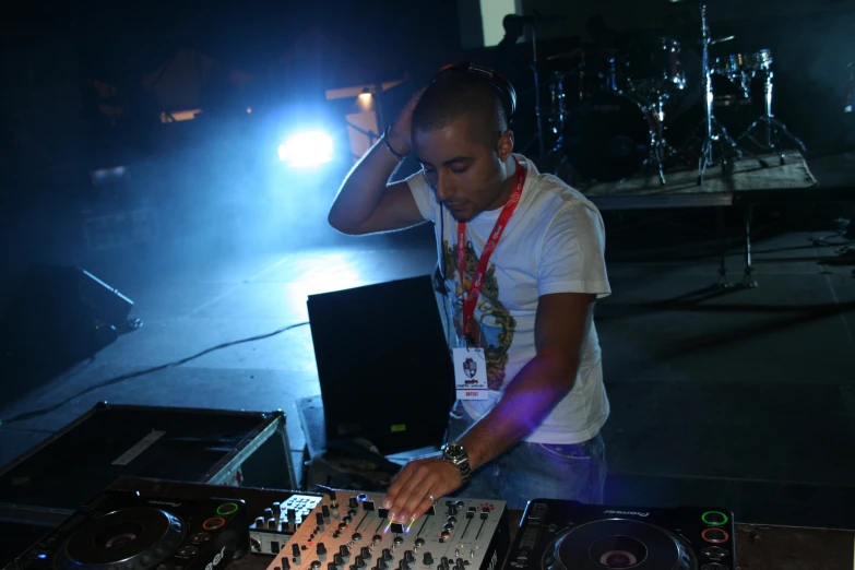 a dj with headphones operating an electronic mixing console