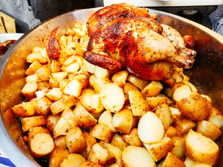 a large metal pan filled with some potatoes and chicken