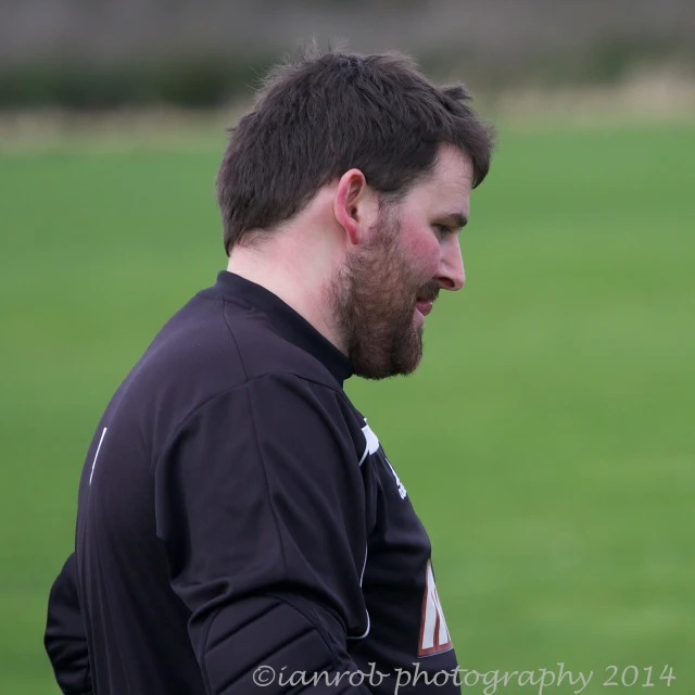 a male in black soccer jersey and ball on field