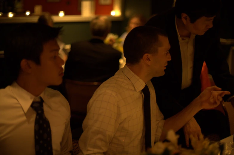 three men sitting at a table with paper hats on their heads