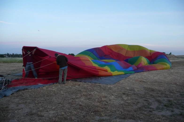 a man fixing the parachutes on top of a large kite