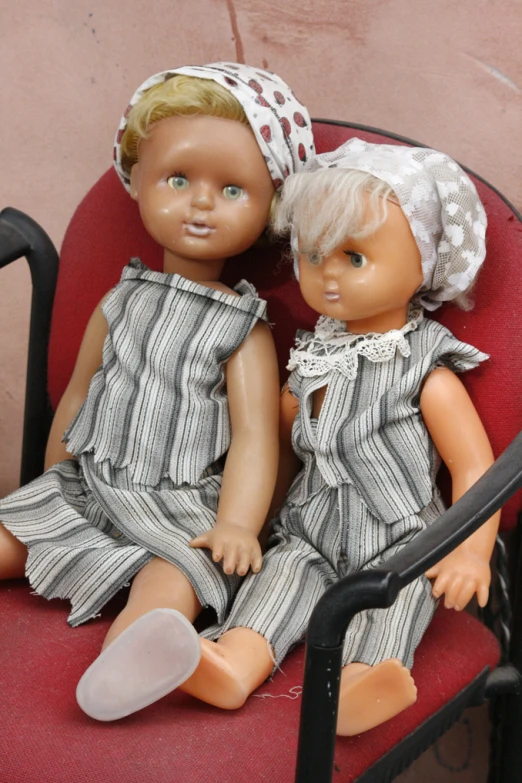two doll heads sitting in an armchair next to each other