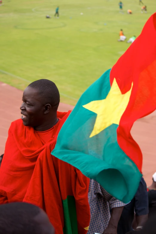 a man holding an african flag while standing on a field