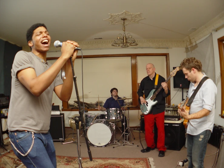 two men singing into a microphone in front of three other musicians