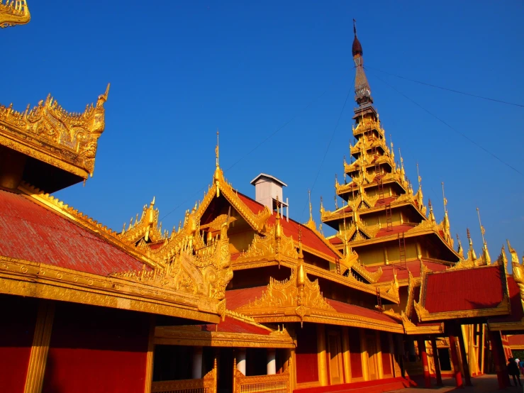 an ornate red and gold building is in the blue sky