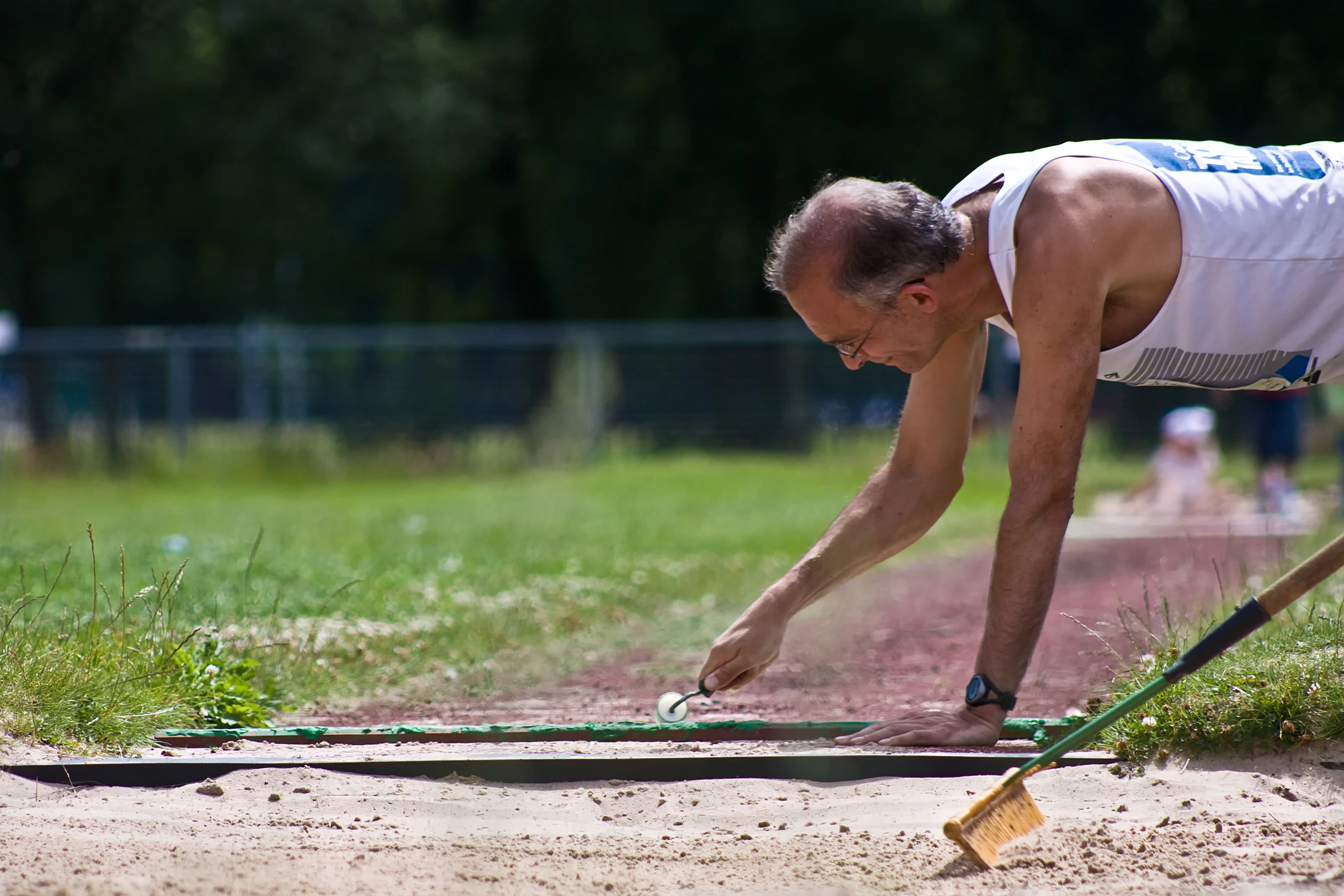 a man bending over in the sand while holding a paddle