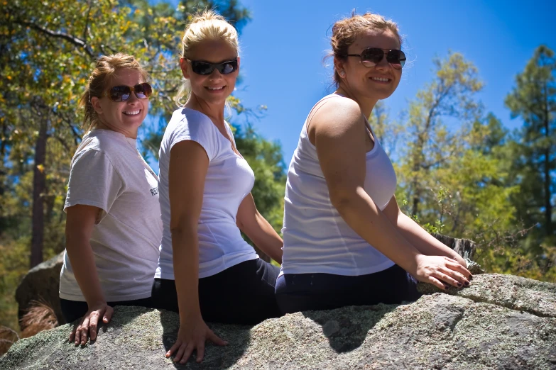 three women sitting on the rocks and smiling for a po