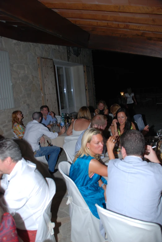 a woman in blue sitting at a table with lots of people