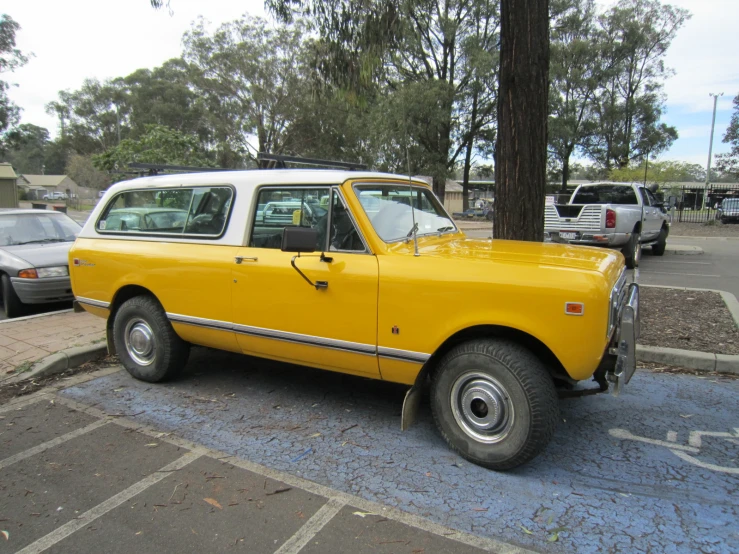 an old yellow car sits next to two older cars