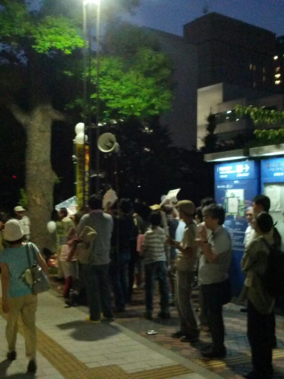 some people stand together waiting to cross the street at night