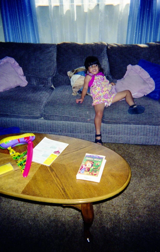 the girl is sitting on the couch looking at the toy