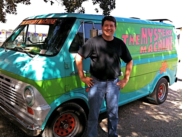 man with black shirt standing beside colorful van