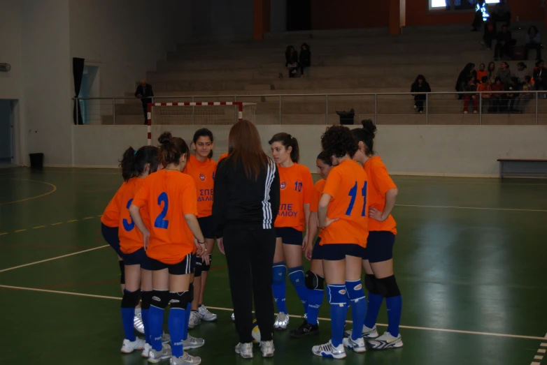 a group of girls wearing orange and blue uniforms are huddled together