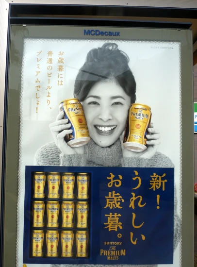 a billboard board with a woman holding up a set of can of beer