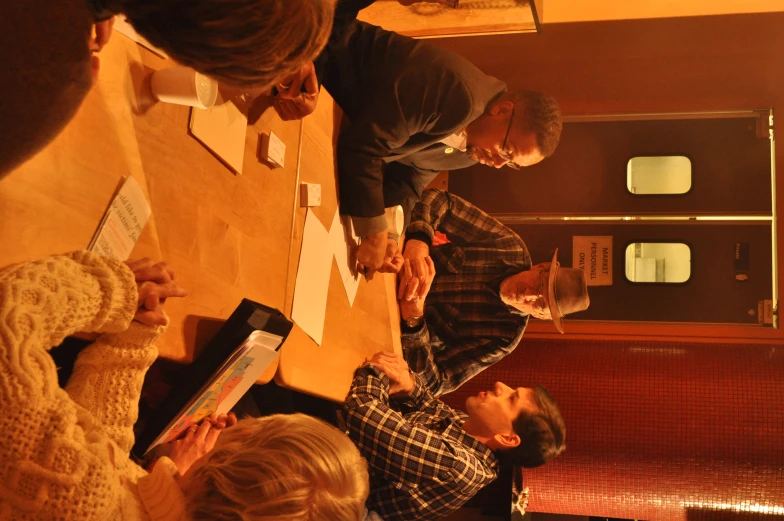 four men and three women sitting at a long table looking at papers