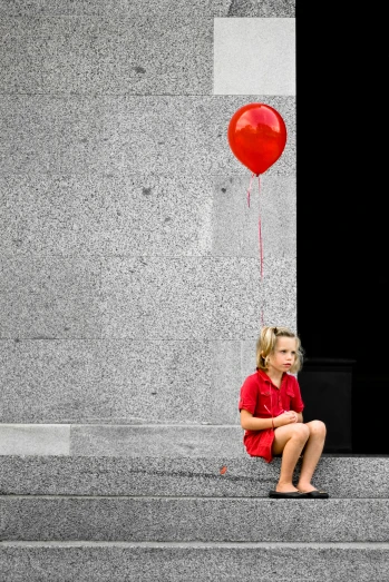 a girl sits on the steps with a balloon