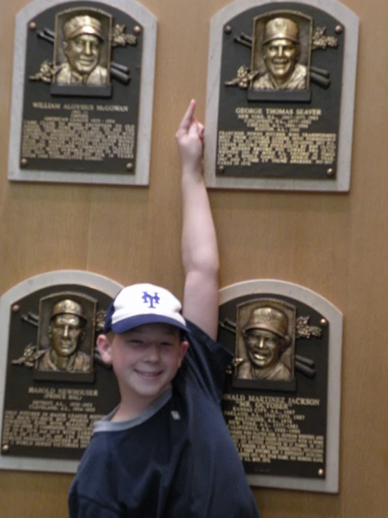 a boy is smiling next to several baseball trophies