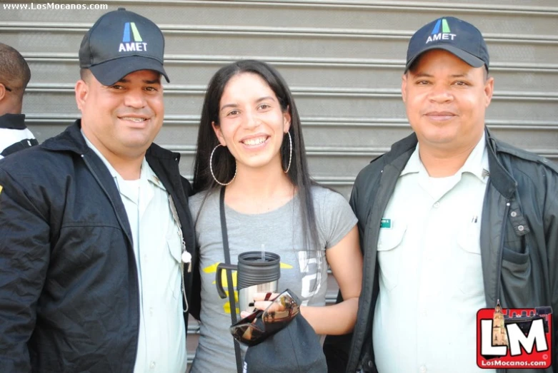 two men and a woman pose for the camera while holding coffee