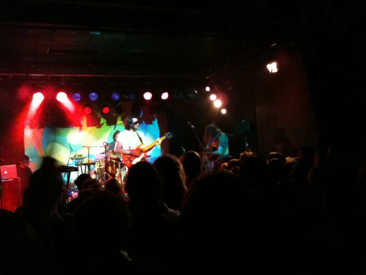 a concert in a dark room with a bunch of people on stage