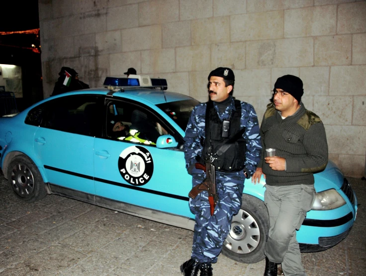 two cops in camouflage standing next to a car