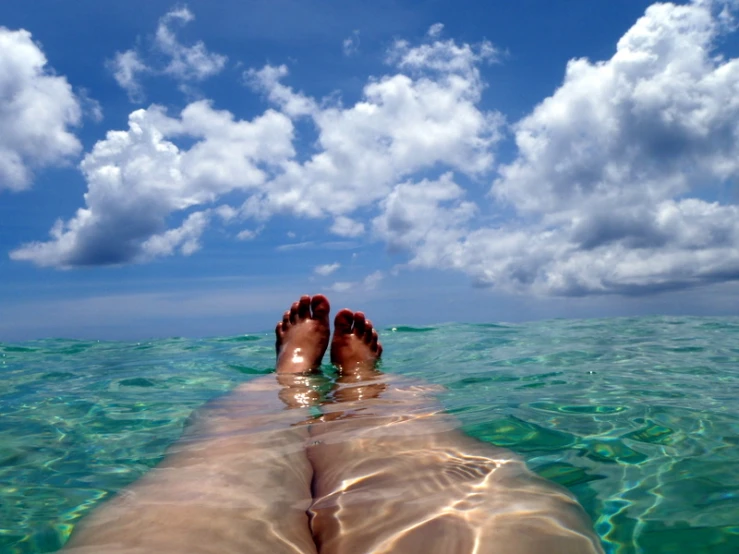 two feet standing in the water looking at the sky