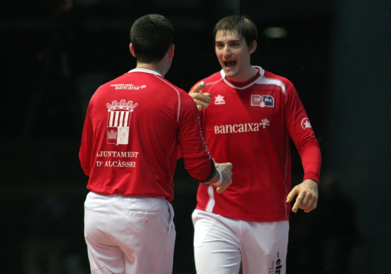 two men in red shirts and white pants standing together