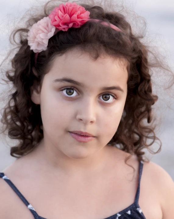 a little girl with her hair up and wearing a flower in her hair