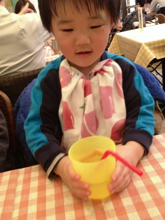 a little asian child drinking from a yellow bowl