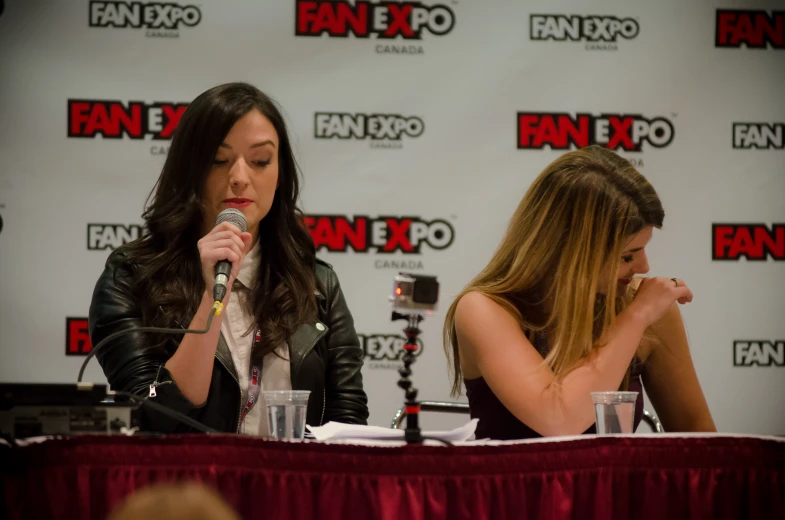 two women sitting at a table and microphone