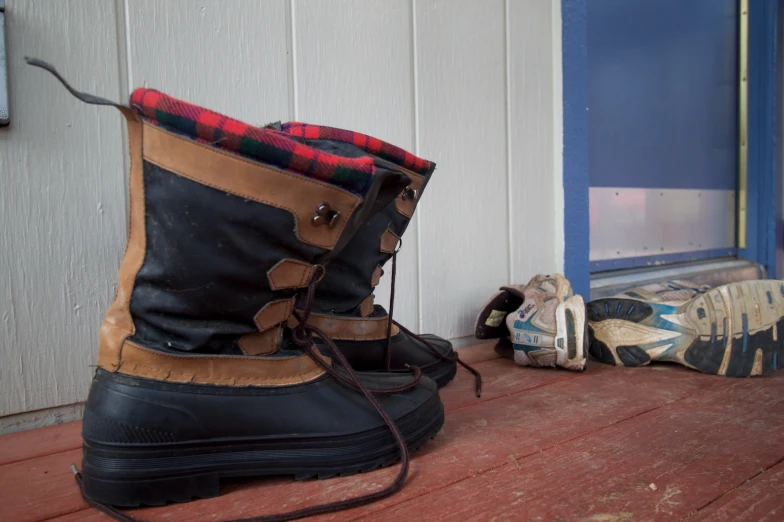 a pair of boots sit next to a pair of snow shoes