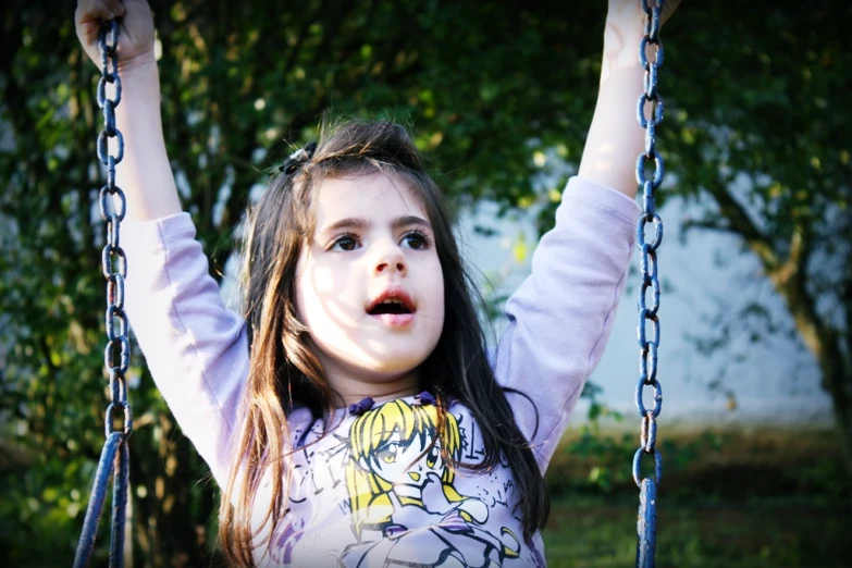 a  on a swing with both hands up in the air