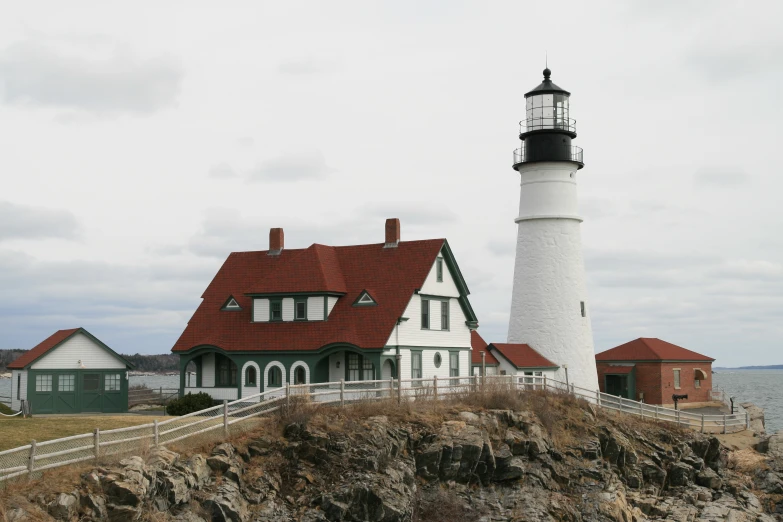 a white lighthouse sitting next to houses on the beach