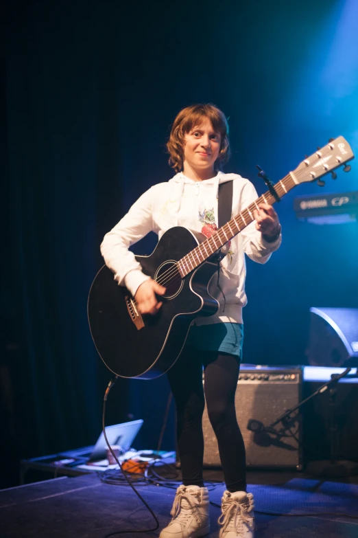 a girl in white and black outfit holding an acoustic guitar