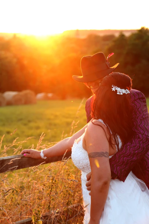 a bride and groom kissing while the sun is setting